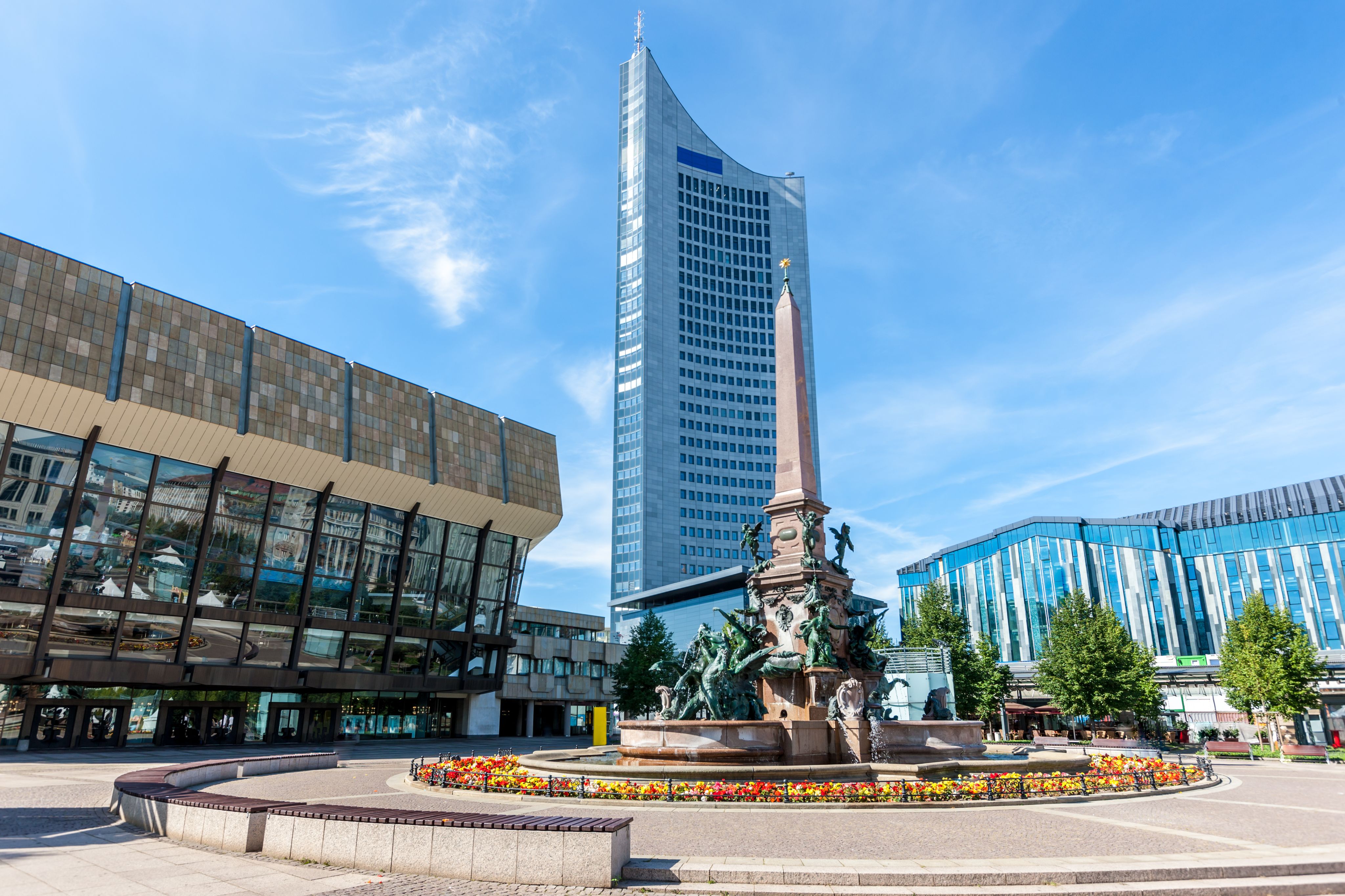 Leipzig city centre: an elaborate fountain and glass-fronted building in the foreground, with a modern skyscraper in the background